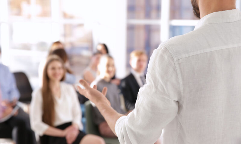 Photo d'une personne de dos s'adressant à une assemblée.